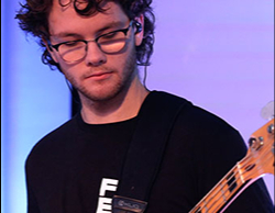 A man looking down at his guitar as he plays on stage