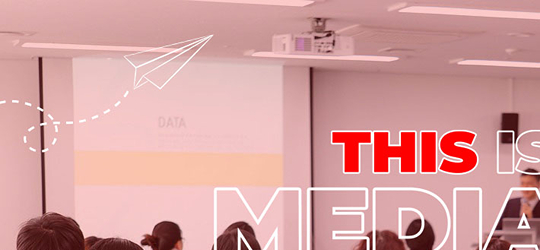 Motion reel styleframe of a red overlaid classroom with the words 'This Is Media' in the corner, and a paper airplane in another corner